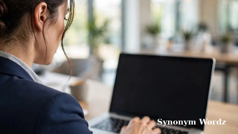 Business professional typing a polite email on a laptop in a bright modern office