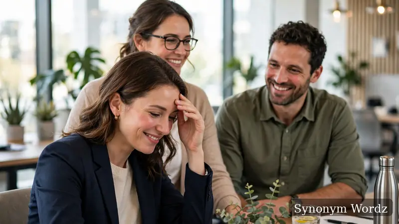 A businesswoman with a sheepish smile touching her forehead during a friendly and supportive office meeting